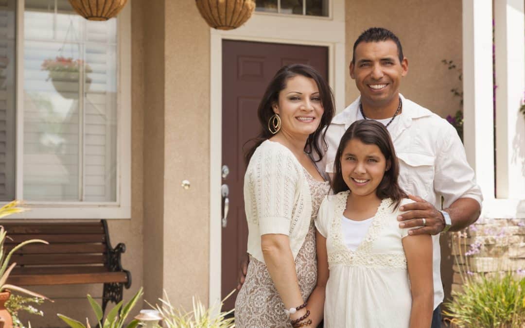 Hispanic family in front of new home