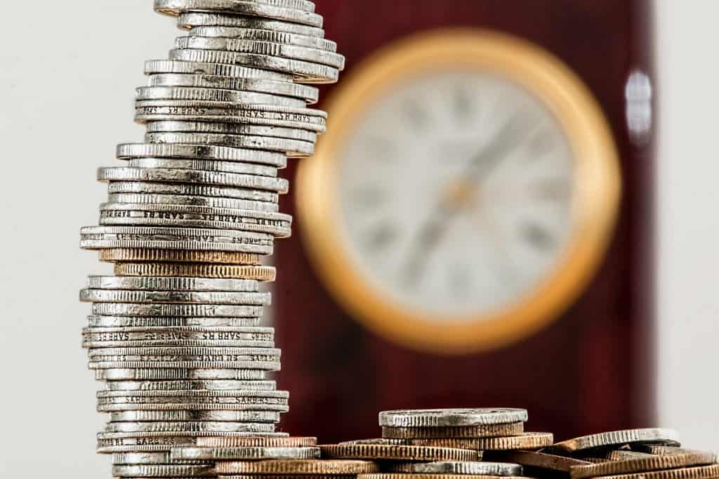 Stack of Coins and Clock Behind