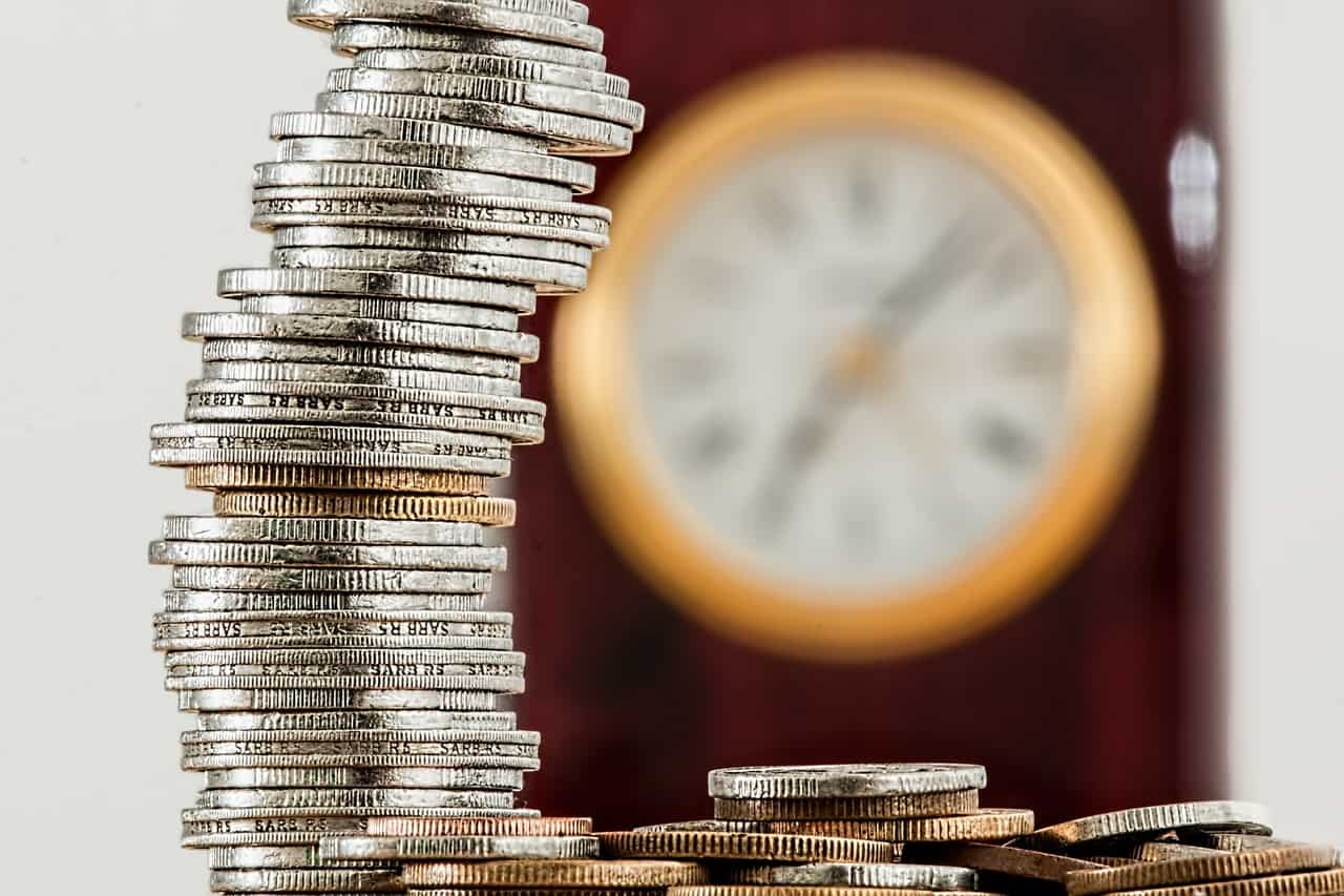 Stack of Coins and Clock Behind Stack of Coins and Clock Behind