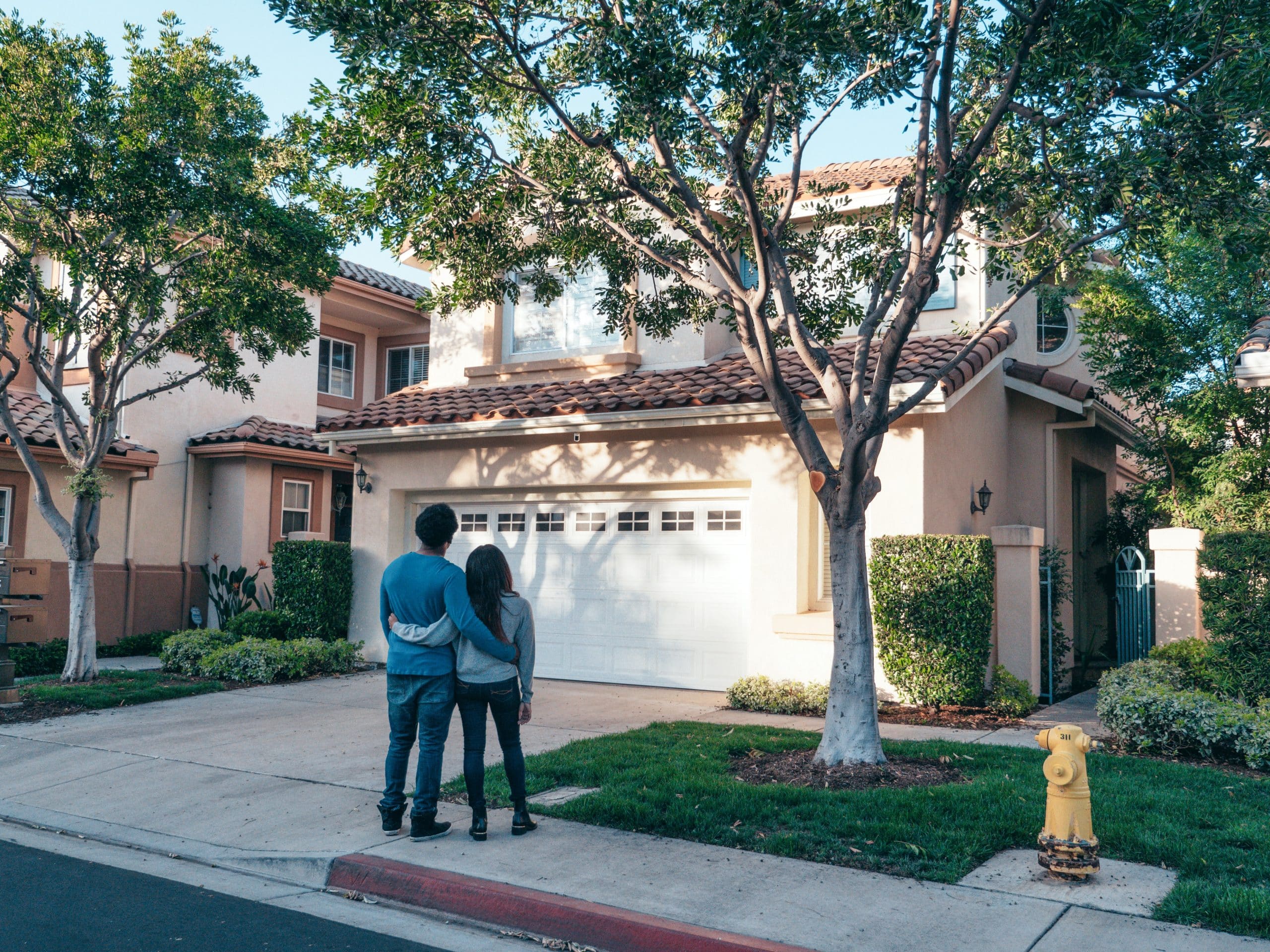 couple hugging looking at house