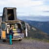 Full-time van lifer standing by camper van in mountain landscape
