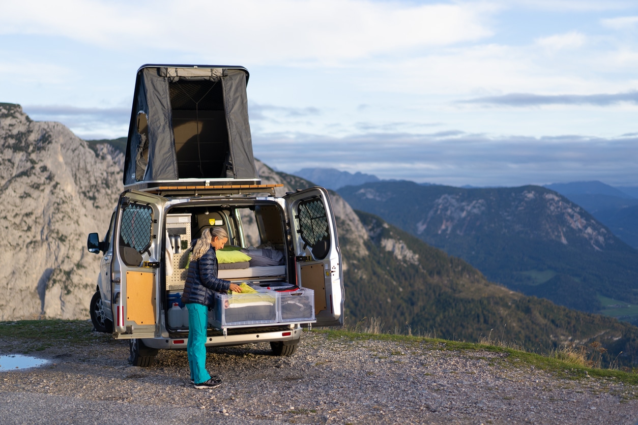 Full-time van lifer standing by camper van in mountain landscape Full-time van lifer standing by camper van in mountain landscape