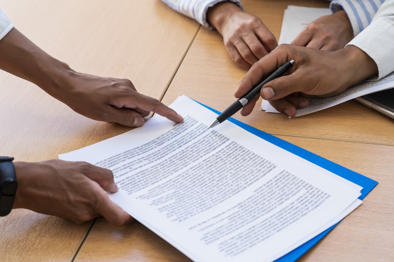 Close-up shot of hands holding and pointing with a pen at documents