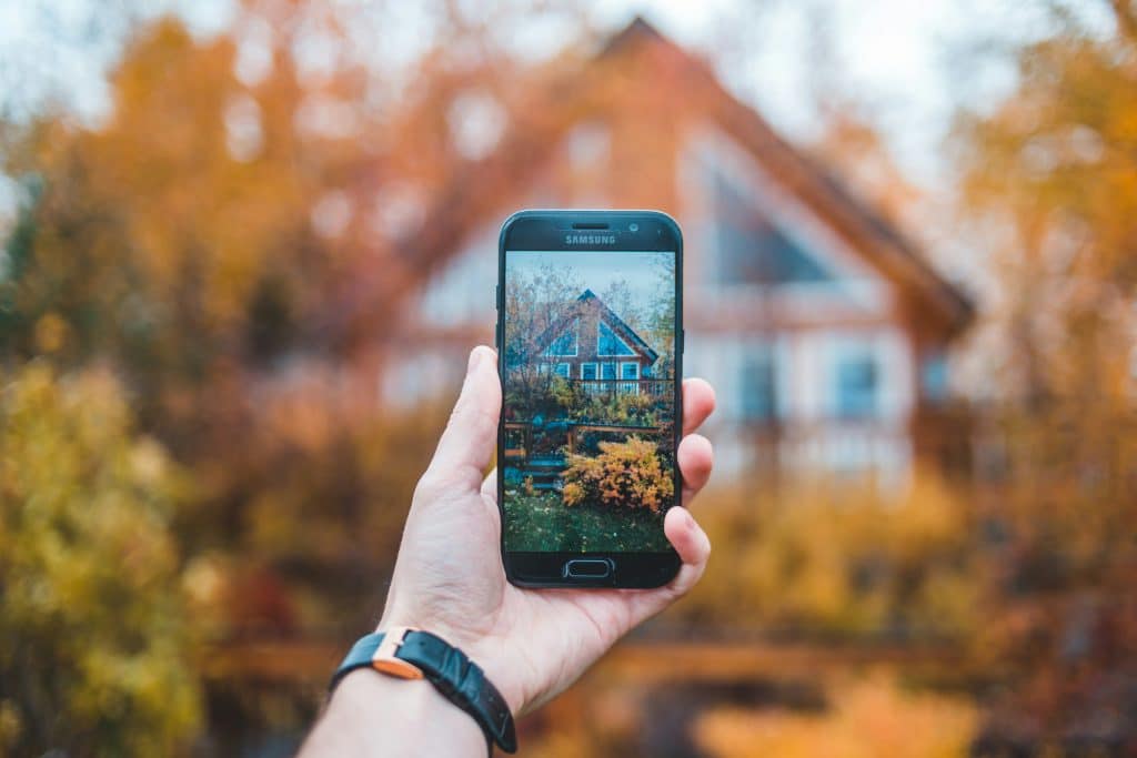Person using a smartphone outside a home, illustrating Figure's AI-agent mortgage and home-equity borrower follow-up workflow