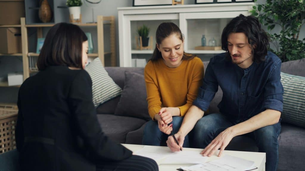 Three people reviewing paperwork in a home, illustrating the HomeSmart and loanDepot mortgage marketing agreement.
