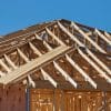 Timber framing and roof trusses on a new home under construction, illustrating homebuilder market conditions