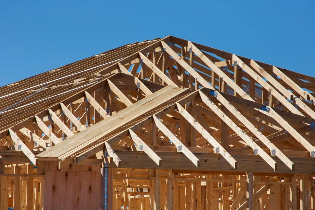 Timber framing and roof trusses on a new home under construction, illustrating homebuilder market conditions