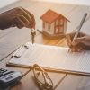Home purchase contract being signed with house keys and model home