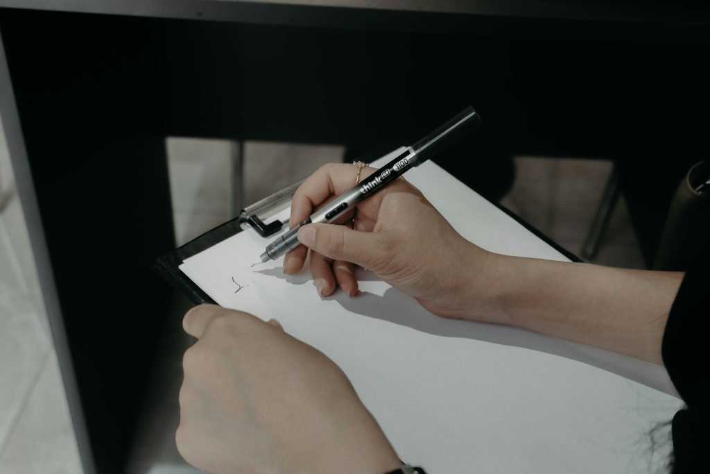 Hands writing on a clipboard illustrating FHA appraisal workflow and UAD 3.6 transition