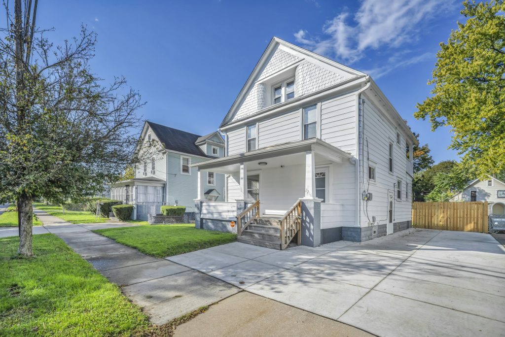 White two-story American home with front porch and lawn, illustrative image for FHA homebuyer down payment assistance