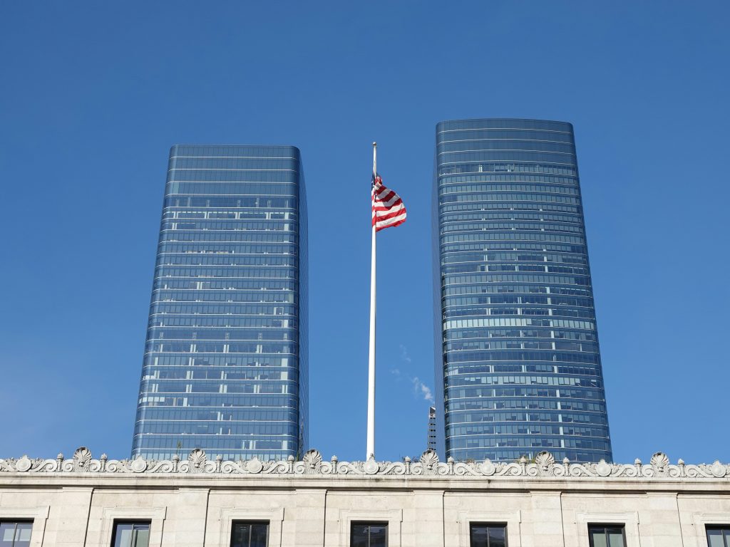 American flag between modern glass office buildings, illustrative photograph for mortgage industry transaction