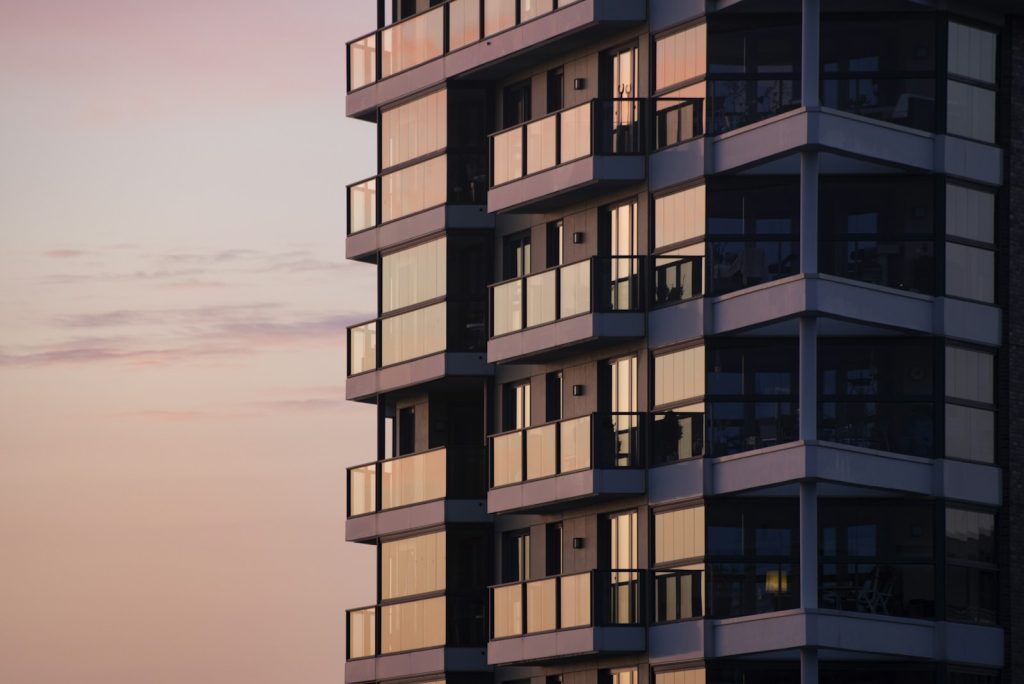 Modern multifamily apartment building with glass balconies, illustrative image for apartment financing survey