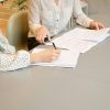 Two people reviewing and signing documents at a desk, illustrating mortgage closing services
