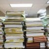 Stacks of paper documents illustrating vendor contracts and invoice analysis