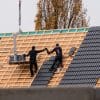 Construction workers installing roof materials on a residential building, illustrative of homebuilding activity
