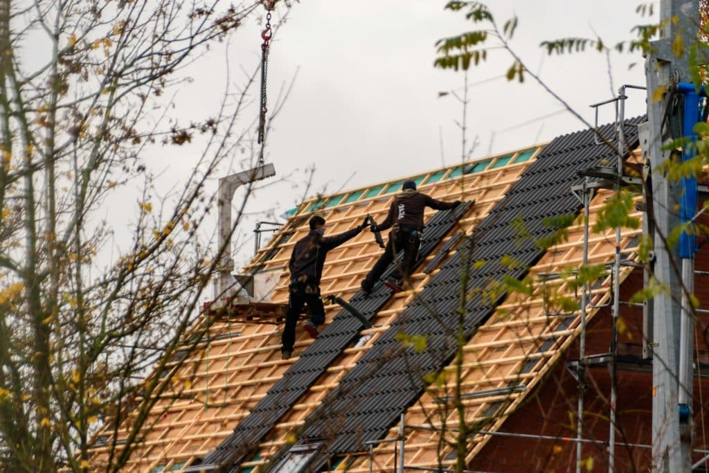 Construction workers installing roofing materials on a house