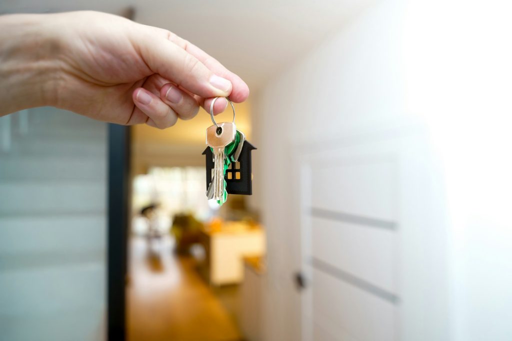 Hand holding a residential door key inside a home, illustrative of rental onboarding