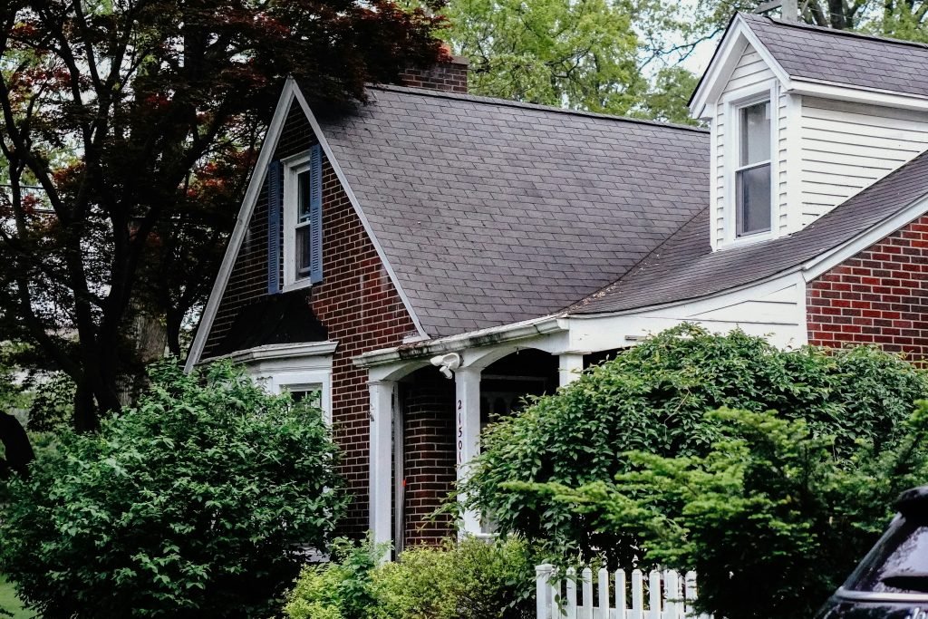 Detached suburban house with dormer windows and landscaped front yard; illustrative image for Freddie Mac delinquent loan auction