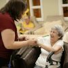 Caregiver assisting older adult with walker, illustrative senior living image