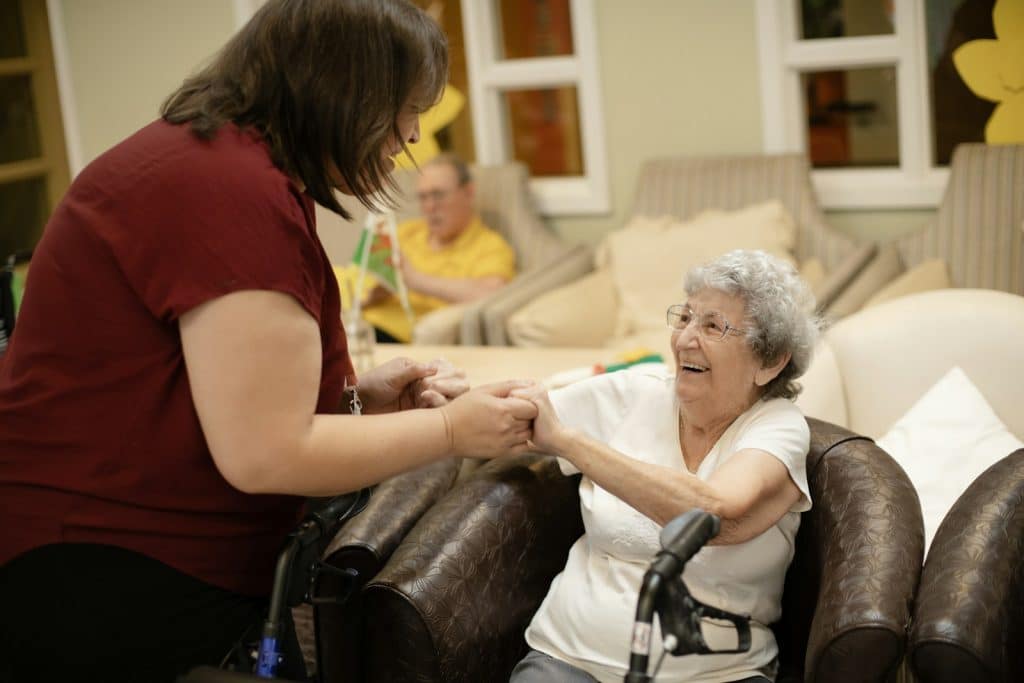 Caregiver assisting older adult with walker, illustrative senior living image